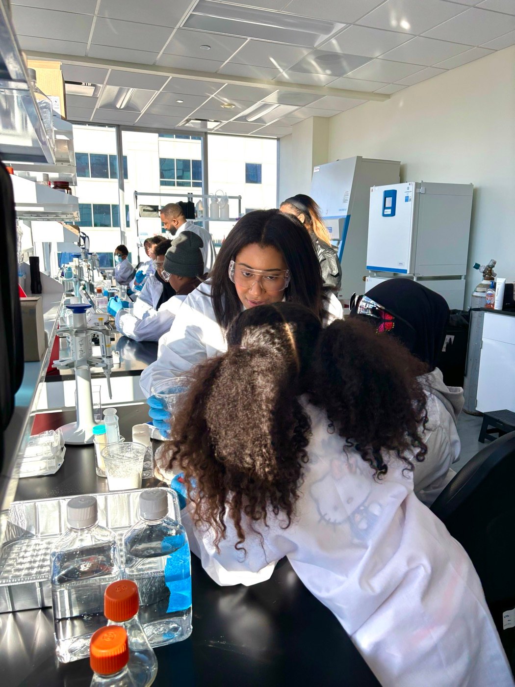 Students in lab coats and safety glasses working at a lab bench