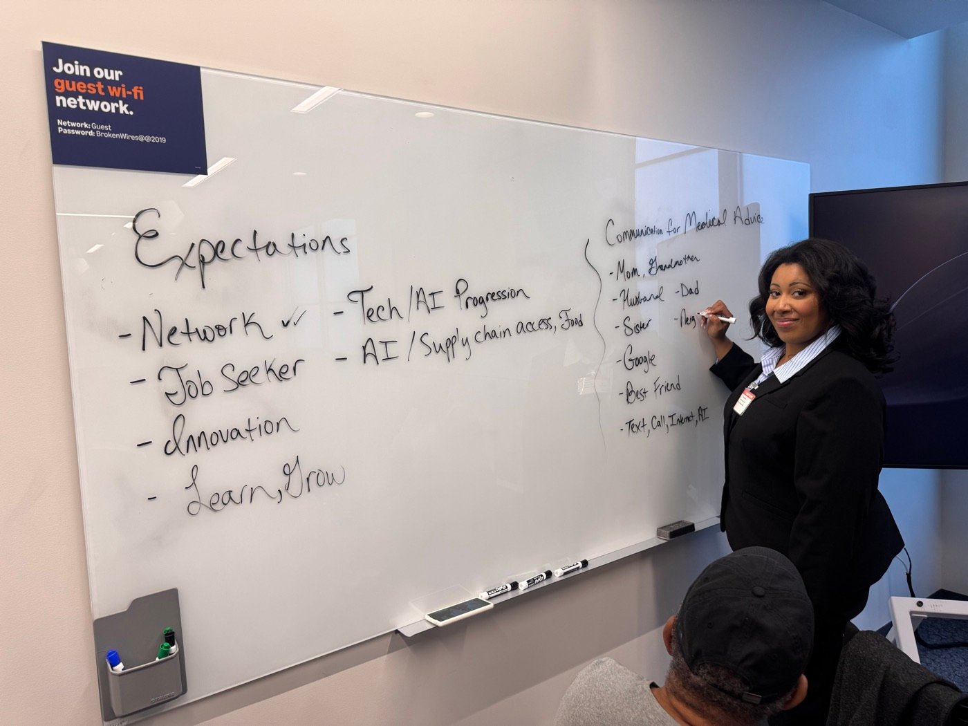Myettia leading a workshop at a whiteboard listing networking, innovation, and growth